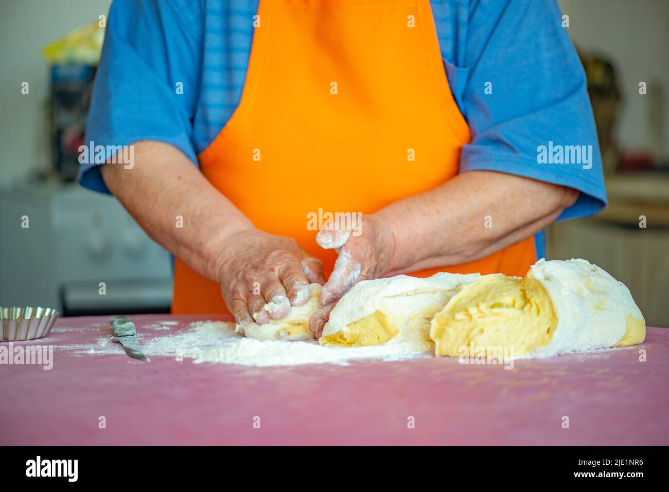 the grandmother kneads dough for Easter cakes on the table Stock Photo