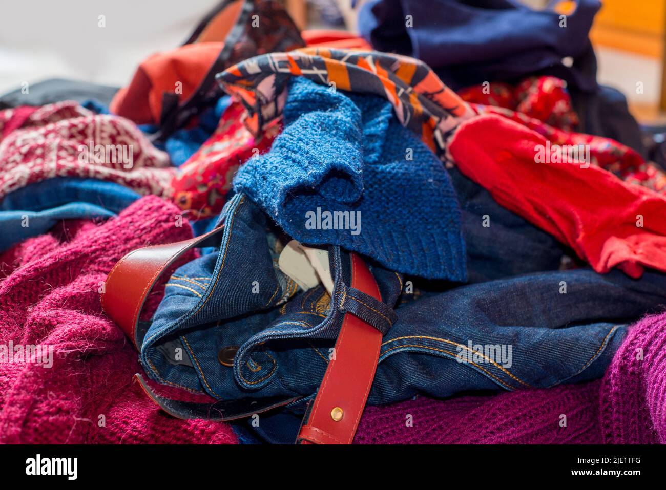 Dump of used clothes. Pile of scattered secondhand clothes on a white