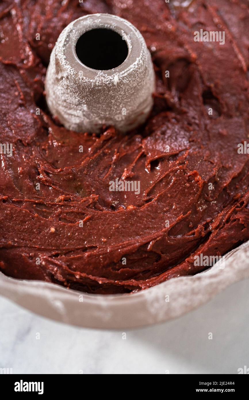 Filling metal bundt cake pan with cake butter to bake red velvet bundt