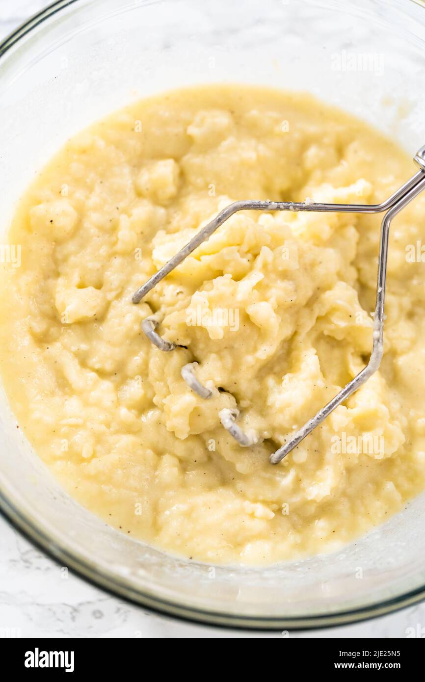 Mashed potatoes. Mashing cooked potatoes in a glass mixing bowl with a