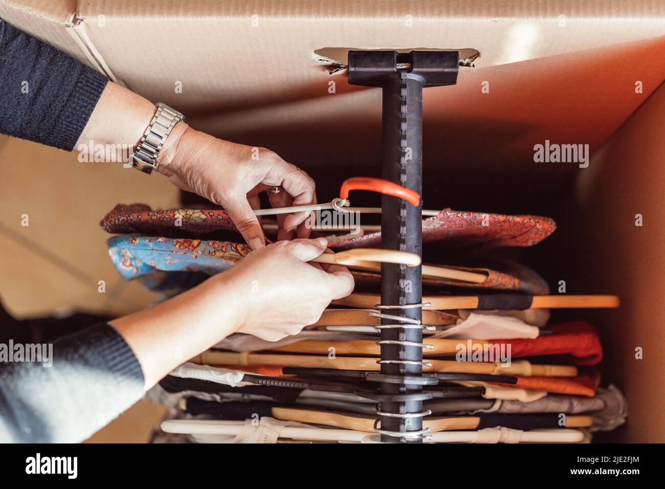 woman's hands hanging blouses inside a coat rack during a move Stock Photo
