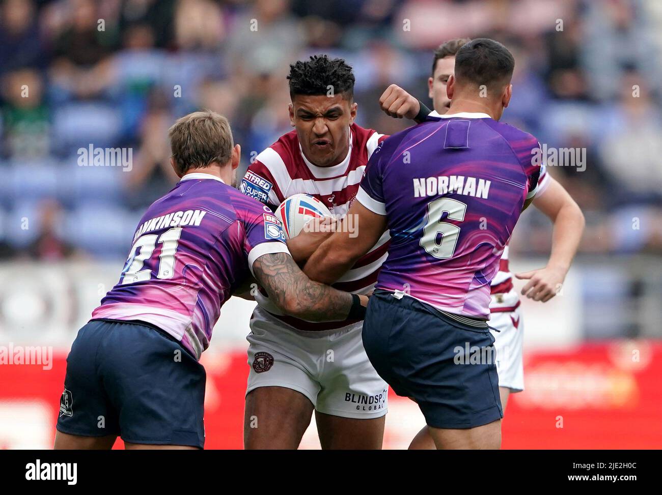 Wigan WarriorsÕ Kai Pearce-Paul is tackled by Toulouse OlympiqueÕs Chris Hankinson (left) and Corey Norman during the Betfred Super League match at the DW Stadium, Wigan. Picture date: Friday June 24, 2022. Stock Photo