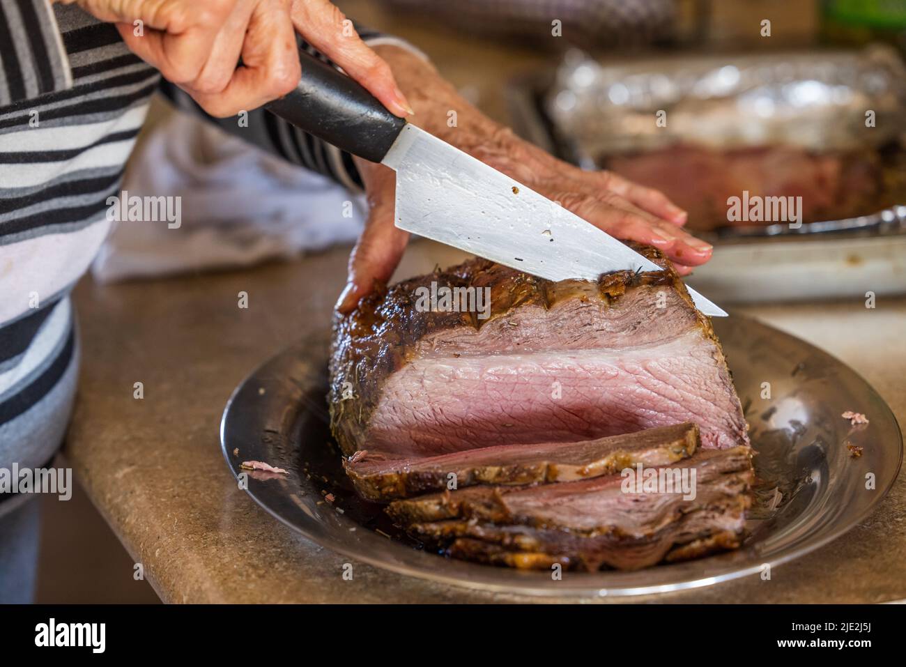 https://c8.alamy.com/comp/2JE2J5J/a-woman-slicing-a-large-prime-rib-beef-roast-that-was-baked-and-roasted-in-the-oven-by-a-home-gourmet-chef-for-a-holiday-christmas-dinner-2JE2J5J.jpg
