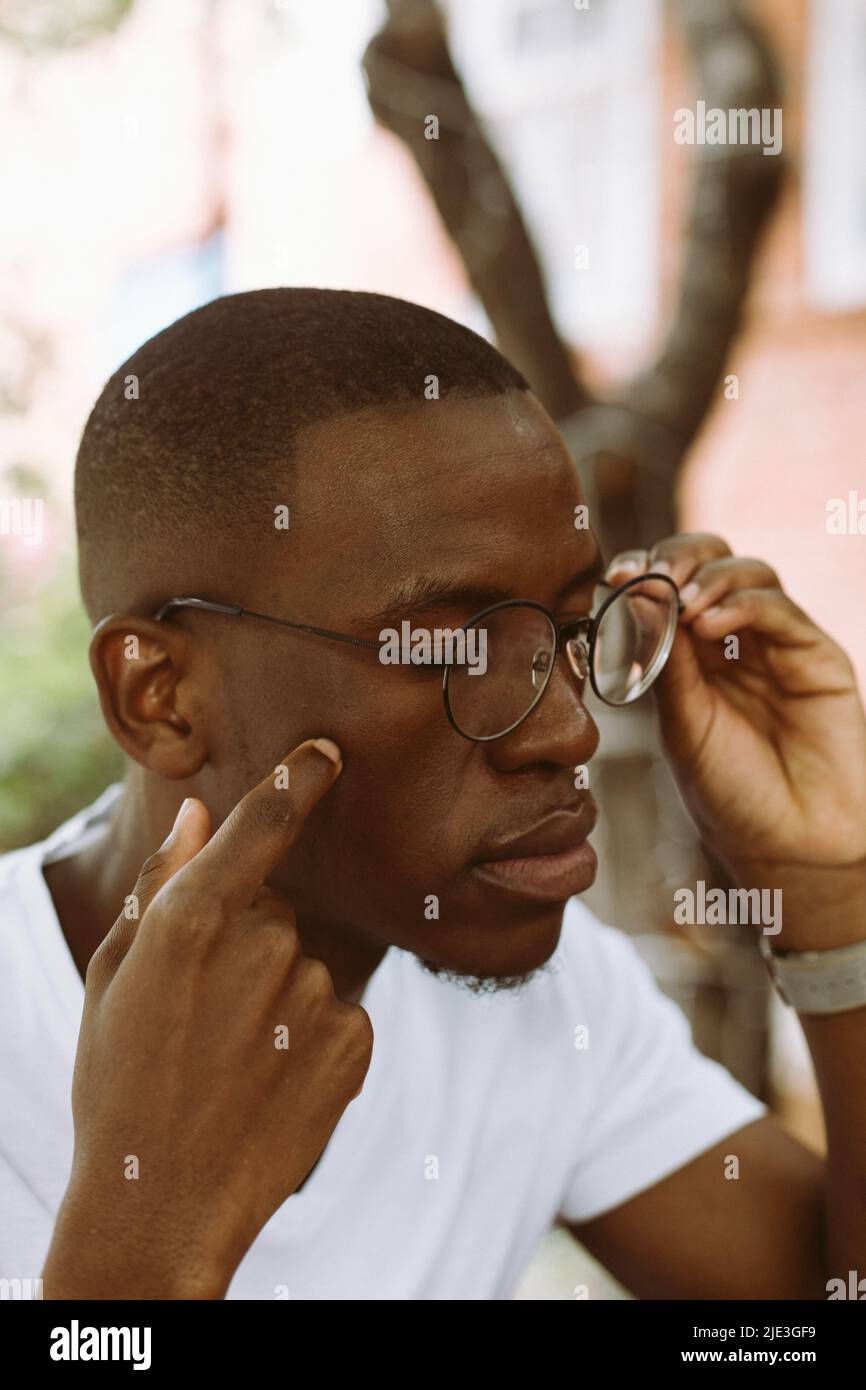 Exhausted dark skin man taking off glasses, touching and rubbing his