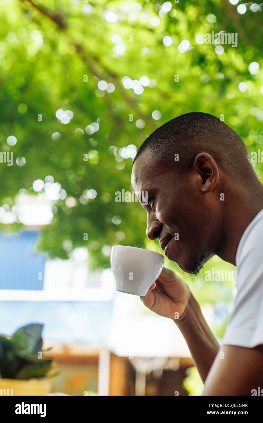 Confident and successful multiracial businessman drinking coffee and work, chatting online using laptop in street cafe Stock Photo