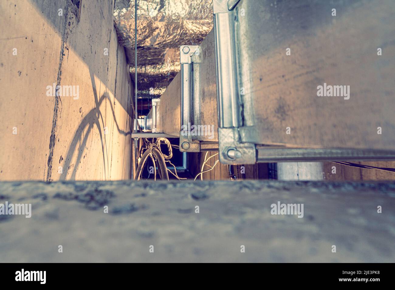 installation of ventilation ducts and cable lines in the technological channels of a monolithic building, selective focus and cold toning Stock Photo