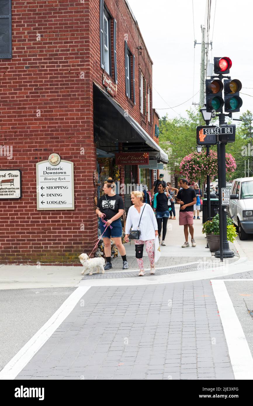 BLOWING ROCK, NC, USA-20 JUNE 2022: Two woman and dog crossing Sunset Drive at Main St. Busy sidewalk behind. Stock Photo