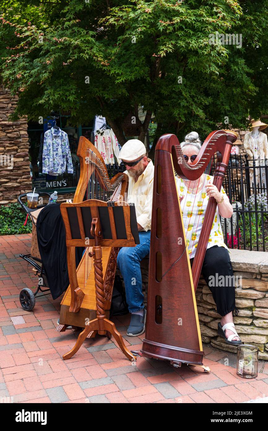 BLOWING ROCK, NC, USA-20 JUNE 2022: Senior man and woman busking with small harps on Main Street. Stock Photo