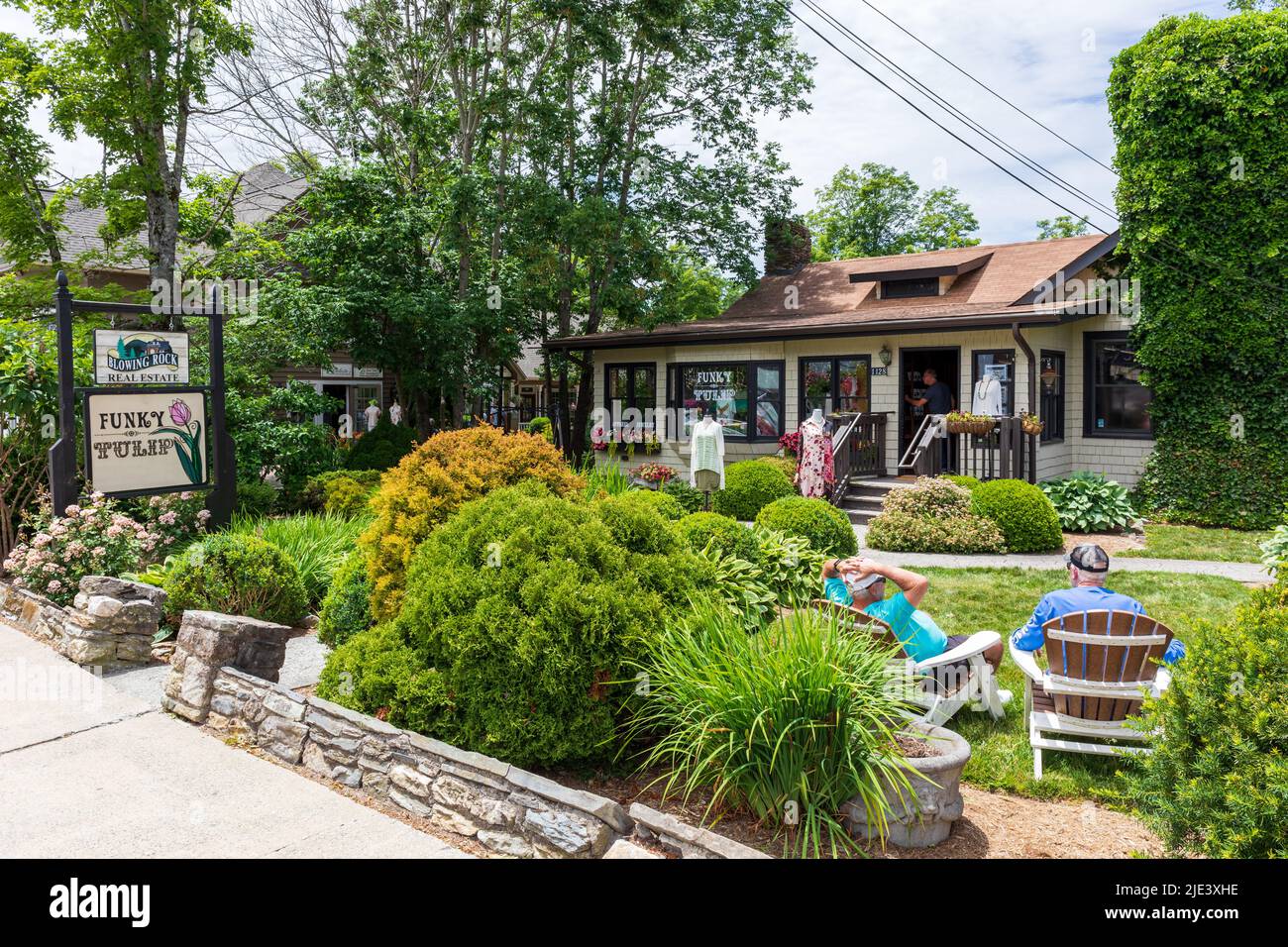 BLOWING ROCK, NC, USA-20 JUNE 2022: The Funky Tulip clothing store on Main St.  Two men sit in front garden. Stock Photo