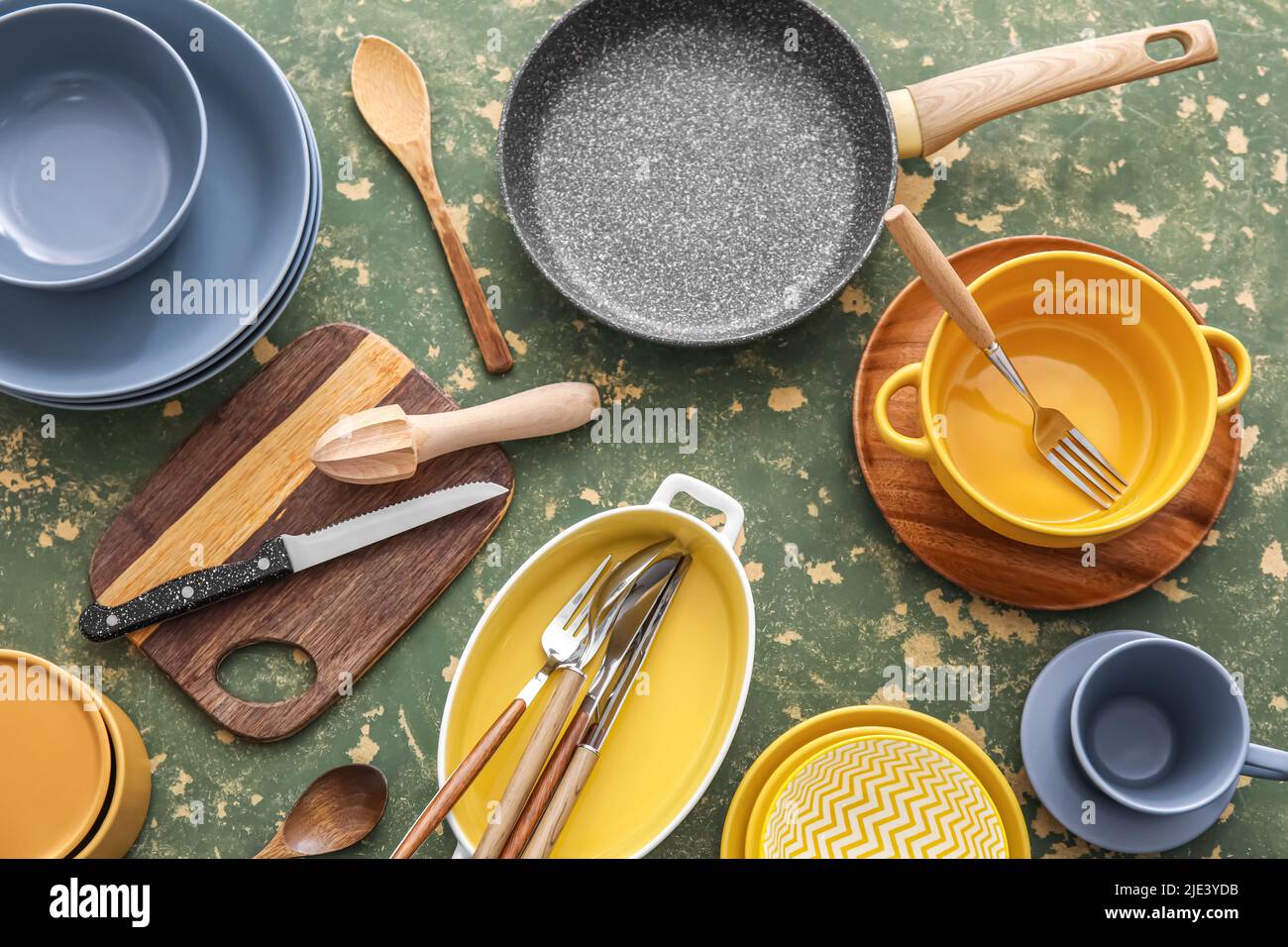Different dinnerware and kitchen utensils on green background Stock