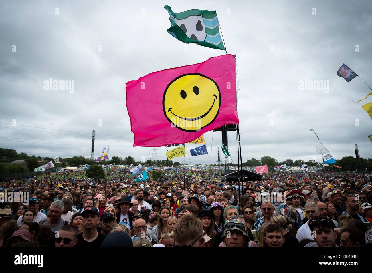 Glastonbury, UK. 24th June 2022. Pink and yellow smiley face flag flies above the Pyramid stage crowd at Glastonbury Festival, at Worthy Farm in Somerset. Picture date: Friday June 24, 2022. Photo credit should read: David Jensen/Empics/Alamy Live News Stock Photo