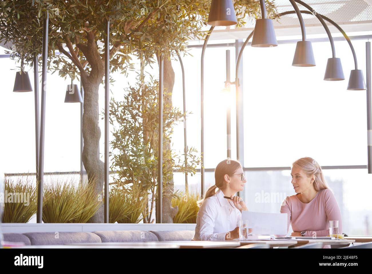 Content creative marketing experts sitting in modern eco cafe and discussing documents while elaborating strategy Stock Photo