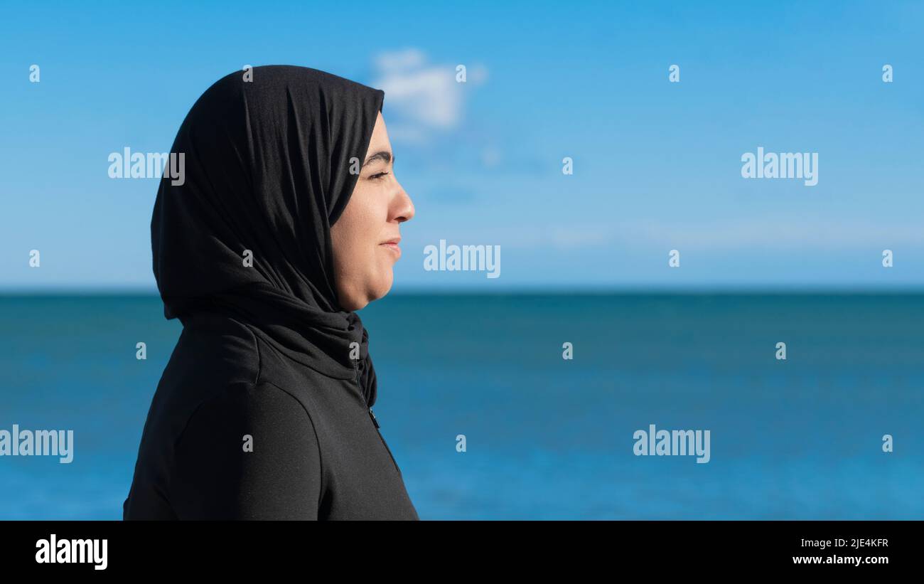 Side shot of a smiling muslim woman with hijab Stock Photo