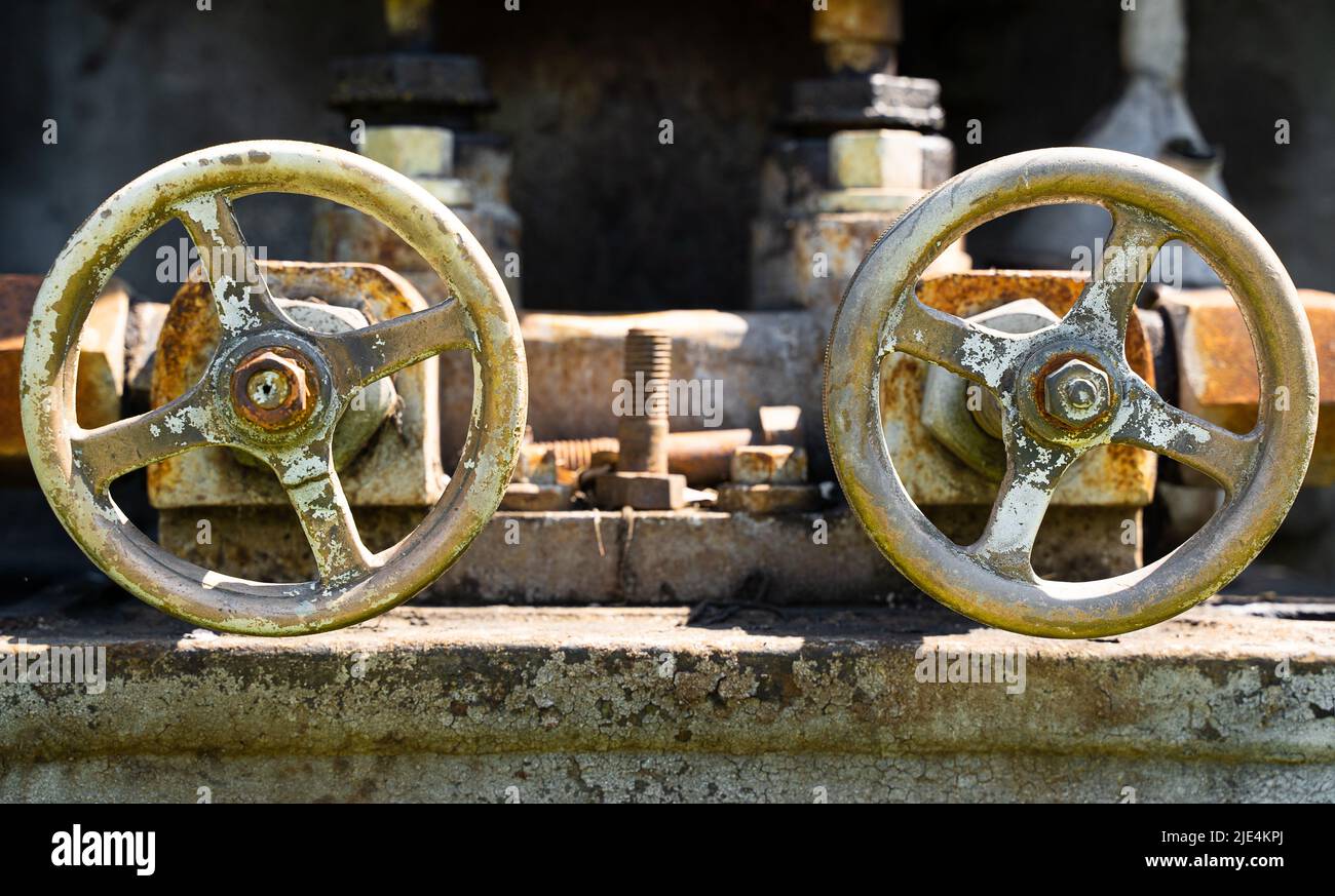 front view closeup of two aged grunge rusted industrial valve wheels Stock Photo