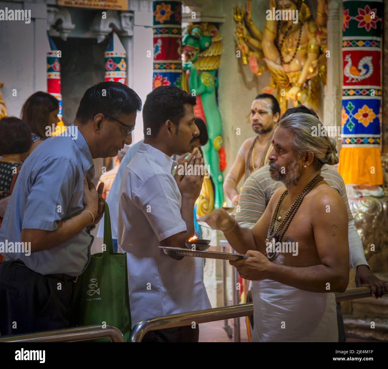 A priest and worshippers in the Sri Veeramakaliamman Temple, Serangoon Road, Little India, Republic of Singapore.  This Hindu temple is one of the old Stock Photo