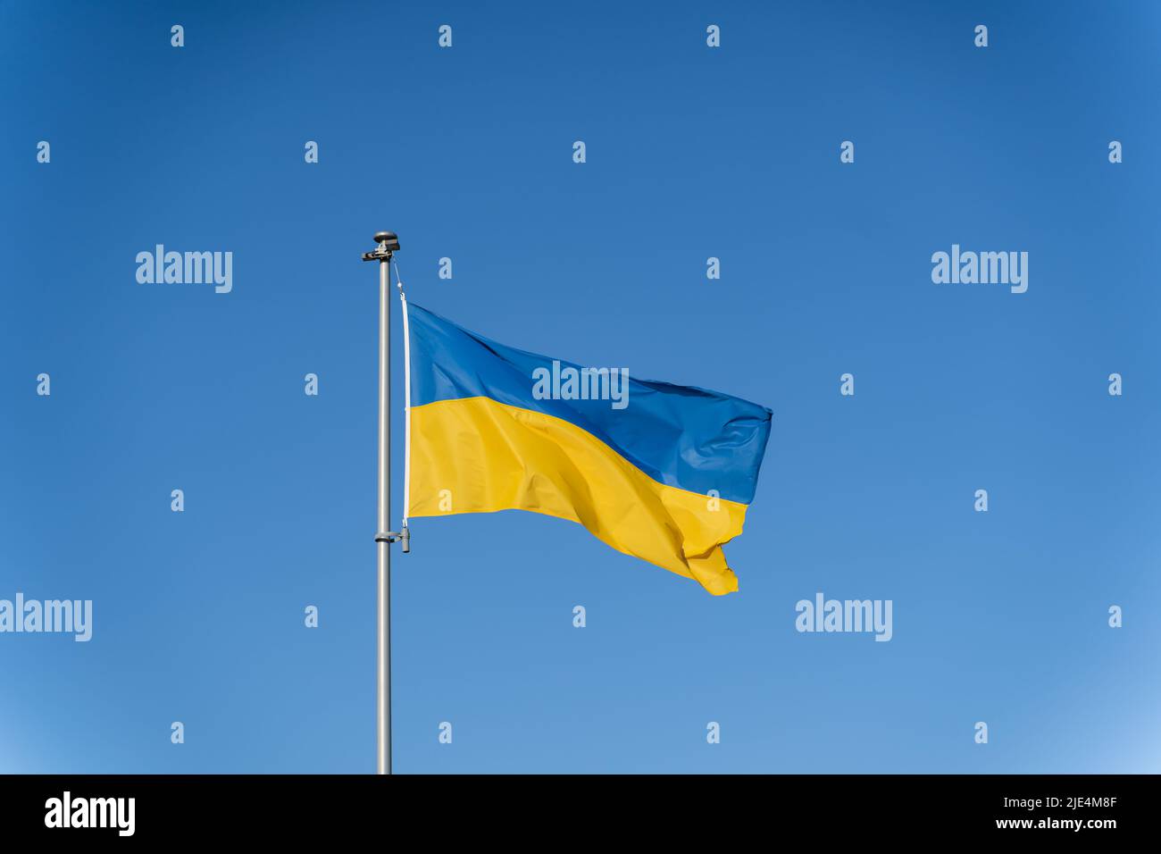 Ukrainian flag of yellow-blue colors on the background of clear blue sky. Stock Photo