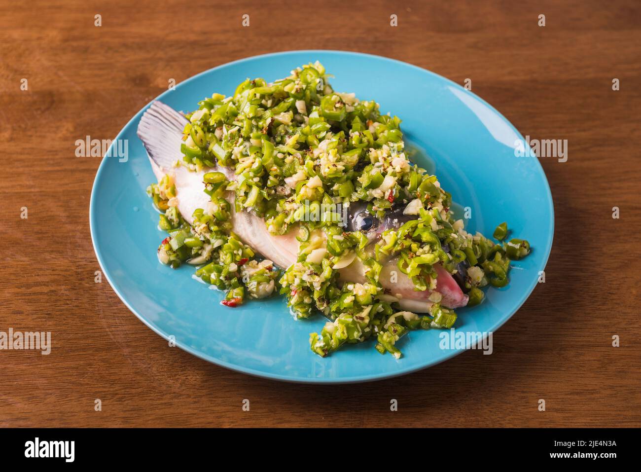 Covered with green chilli sauce fresh oxtail fish head by hand Stock Photo