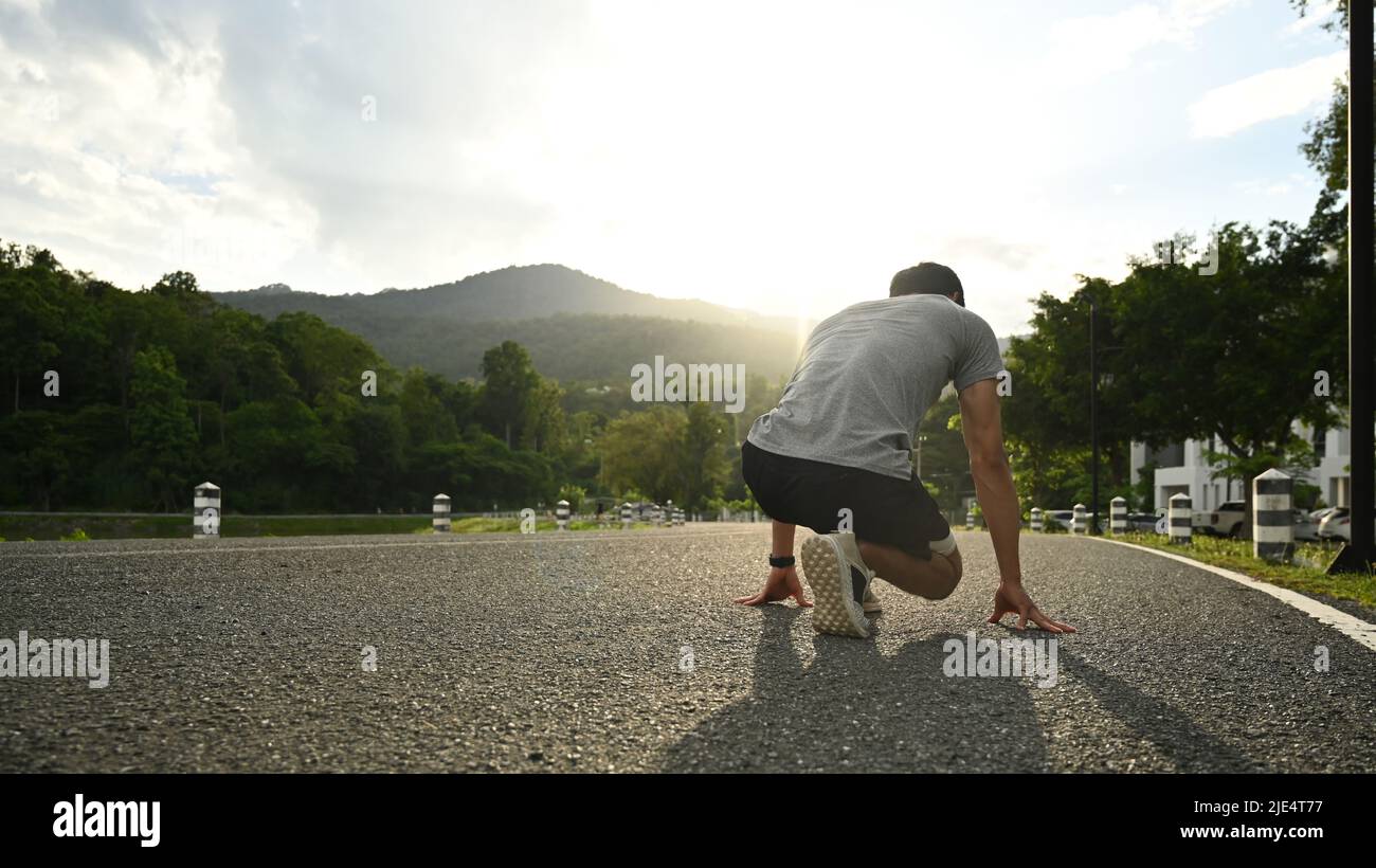 Sports man in starting position ready to run outdoors with beautiful
