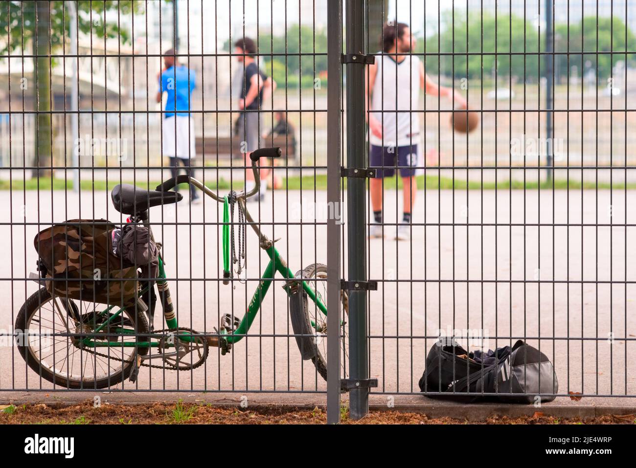 Sports ground, bicycle against men playing basketball Stock Photo