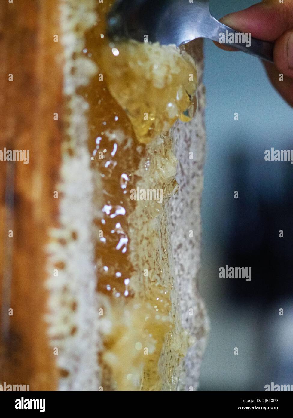 Natural raw honey being filtered ad dripped through a strainer to filter our bees wax Stock