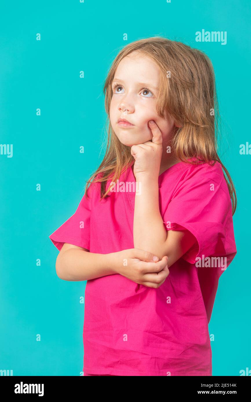 A 6-year-old girl is dressed as a doctor or nurse appears deep in thought. Feminism, STEM, and healthcare concepts. Stock Photo