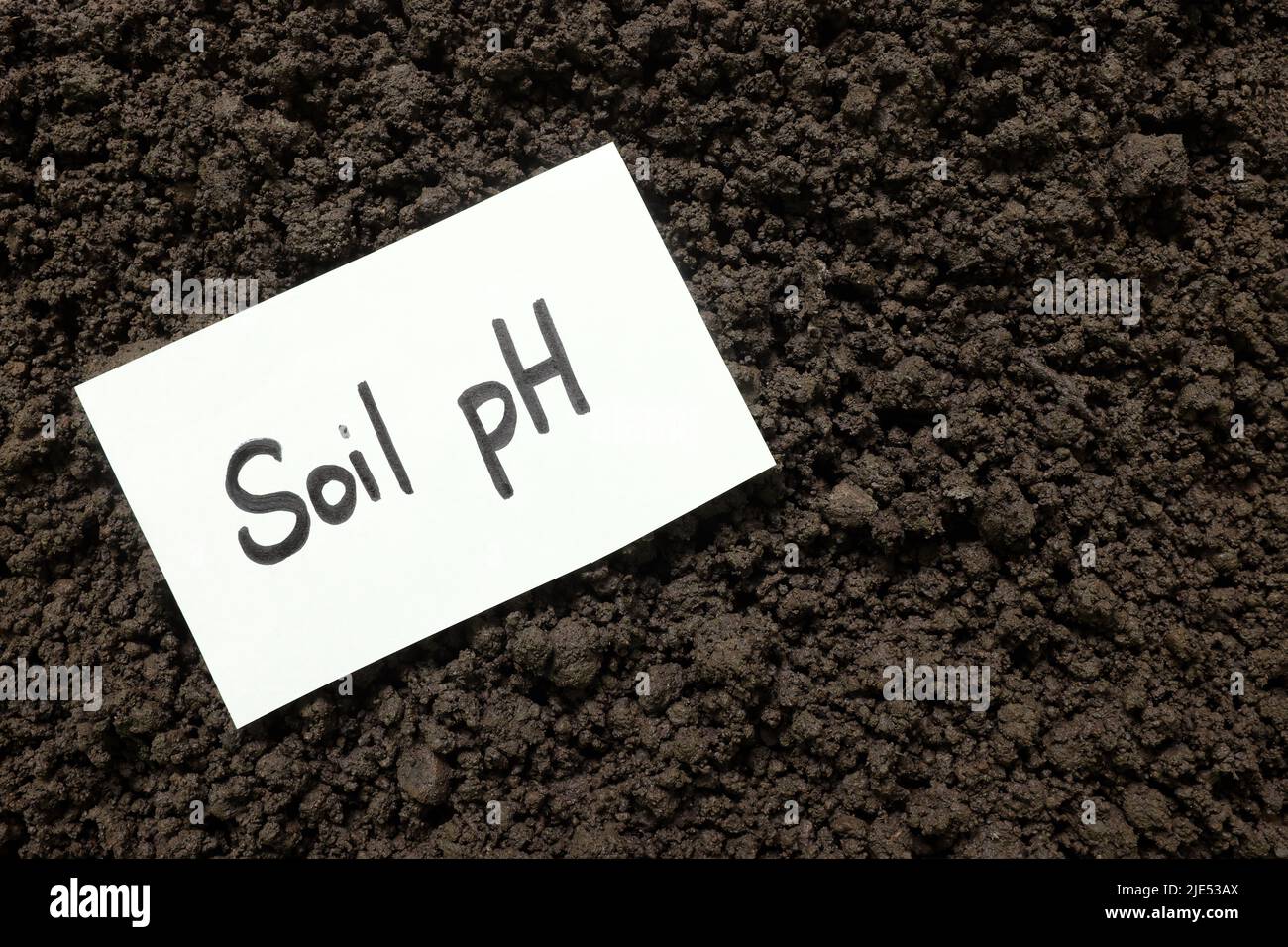 Soil pH agriculture concept. Written word on piece of paper on soil. Stock Photo