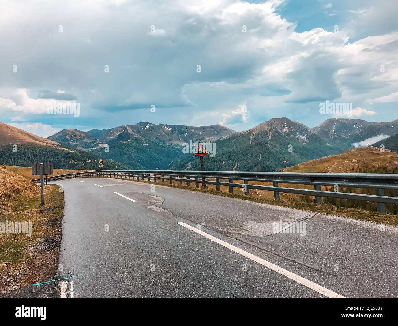 Mountain serpentine in the Alps. An empty road against the backdrop of mountains and cloudy skies. Europe Stock Photo