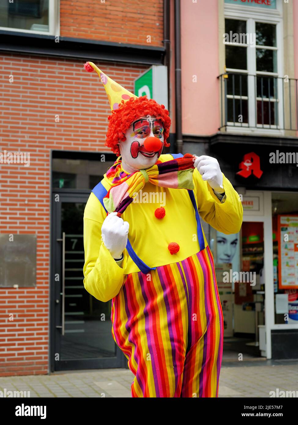Man dressed up as a clown posing for a picture in the Old Town of Düsseldorf/Germany. Old Town is a popular tourist area. Stock Photo
