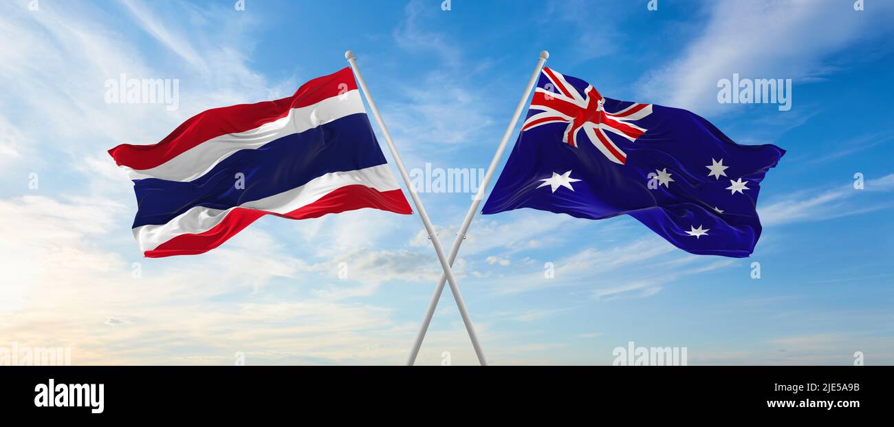 two crossed flags thailand and Australia waving in wind at cloudy sky ...
