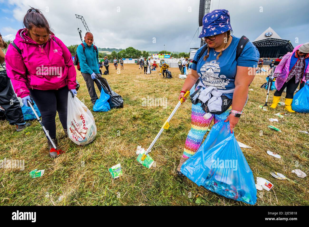 Pilton, UK. 25th June, 2022. Thousands of volunteers (many raising money for charities) clean up the waste left by festival goers the previous night (in this case at the Pyramid Stage). The work is necessary despite the festival motto to 'leave no trace' - The 50th 2022 Glastonbury Festival, Worthy Farm. Glastonbury, Credit: Guy Bell/Alamy Live News Stock Photo