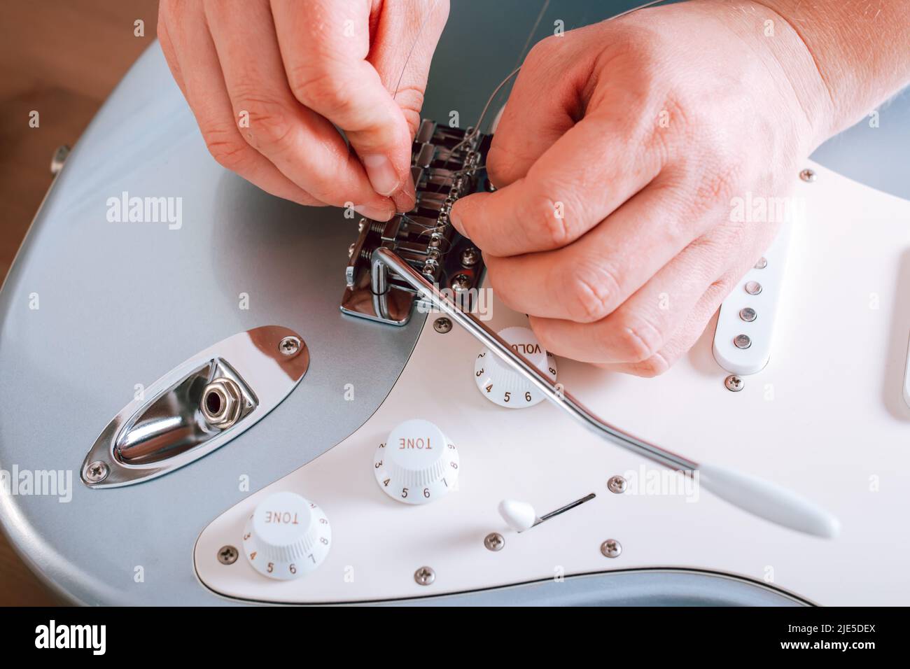 Guitar master restringing electric guitar, top view, hands closeup