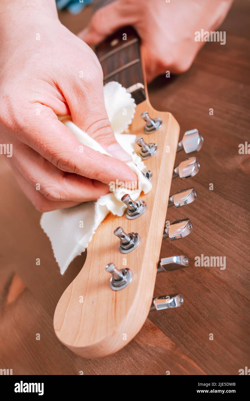 Guitar master polishing headstock of electric guitar, cleaning tuners