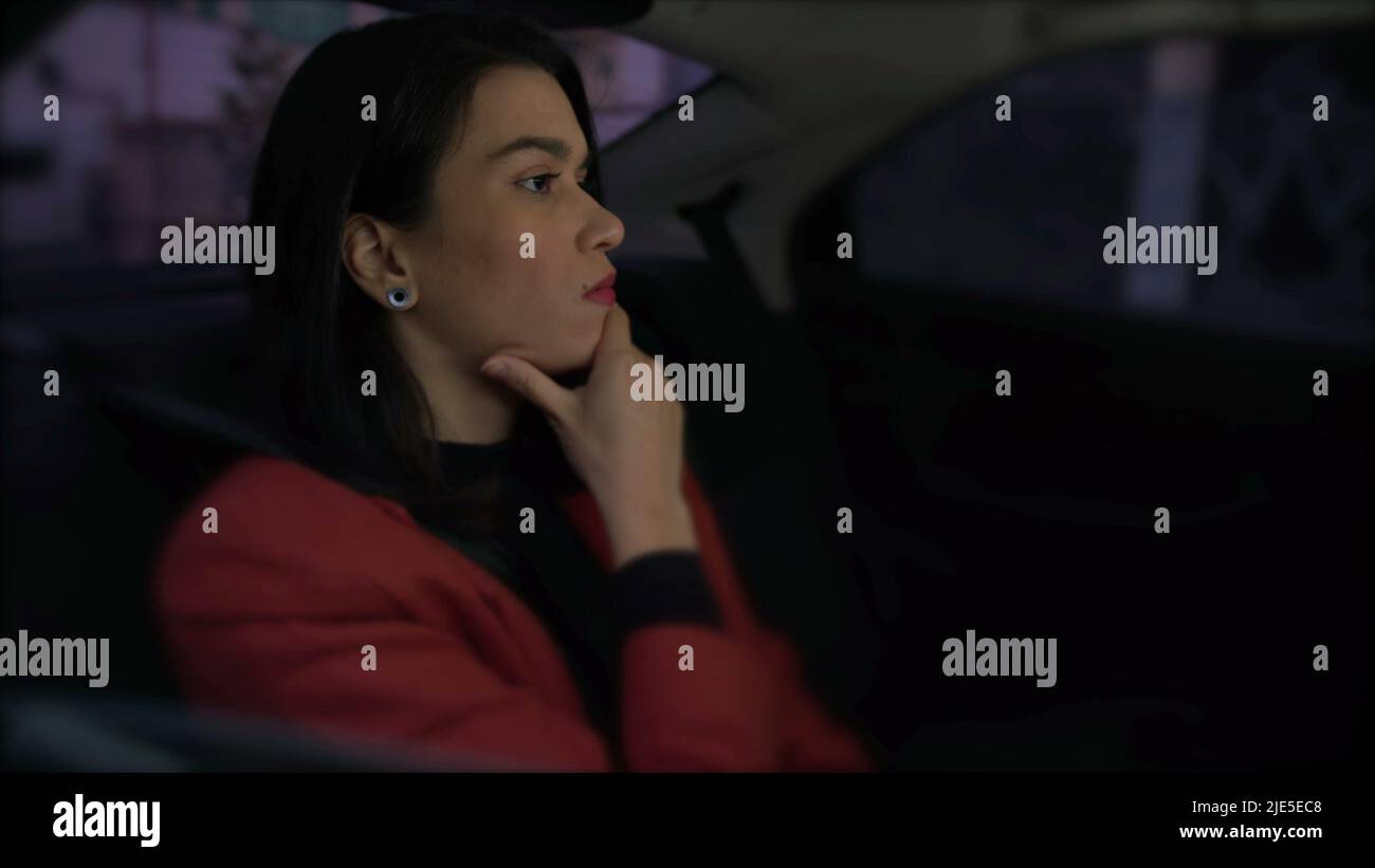 One anxious person stuck in traffic in car backseat. Young woman