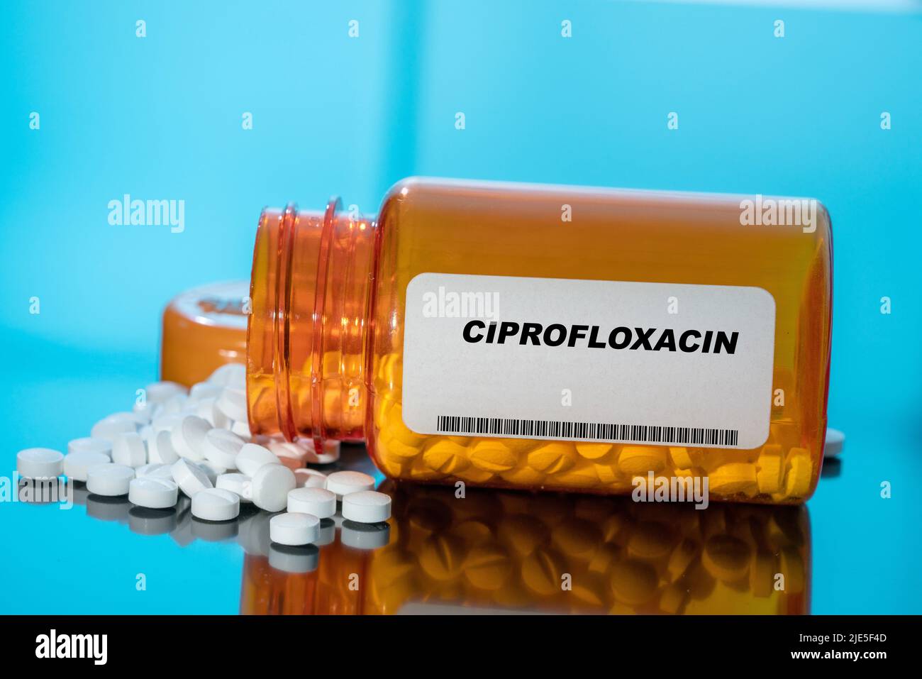 Ciprofloxacin white medical pills and tablets spilling out of a drug bottle. Macro top down view with copy space. Stock Photo