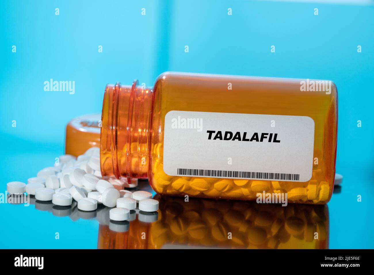 Tadalafil white medical pills and tablets spilling out of a drug bottle. Macro top down view with copy space. Stock Photo