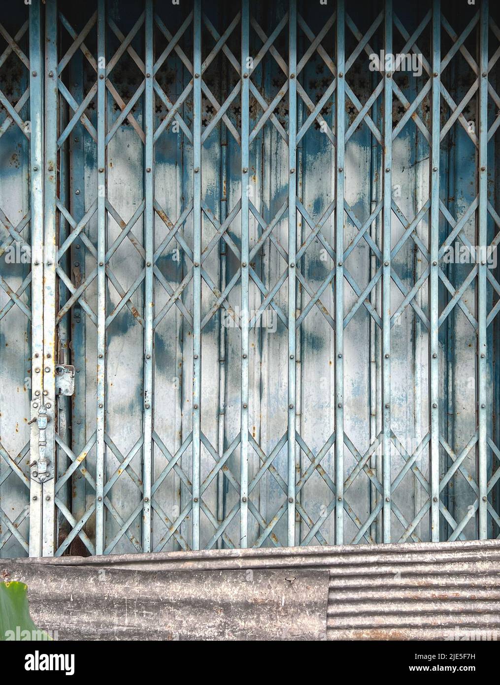 Gate folding. folding metal gate with lock and zinc, galvanized reparing panels of the building, vintage style building folding gate. Stock Photo