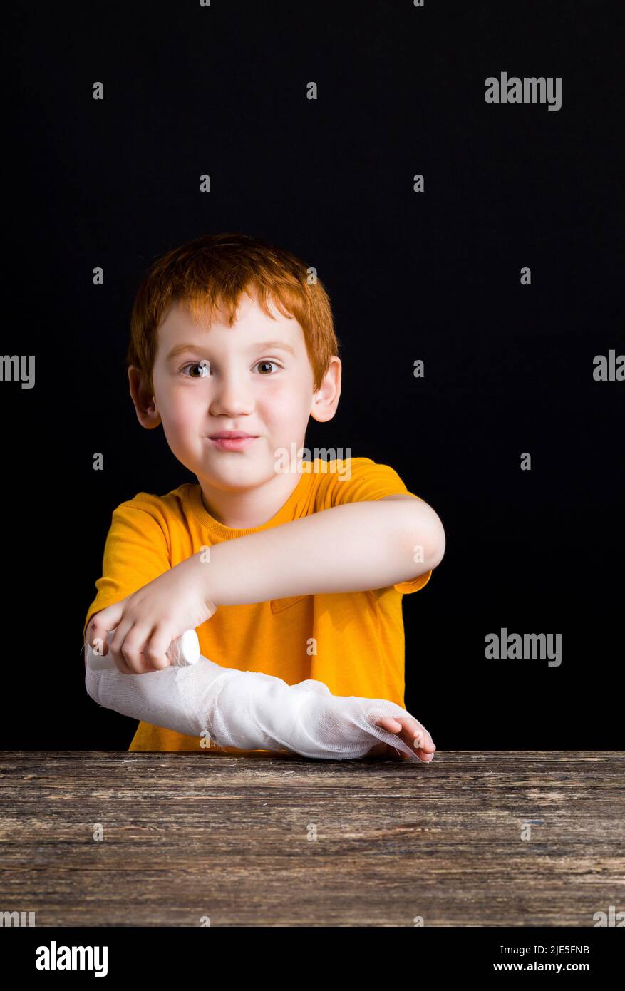 a beautiful boy with red hair with a damaged hand and fingers bandages