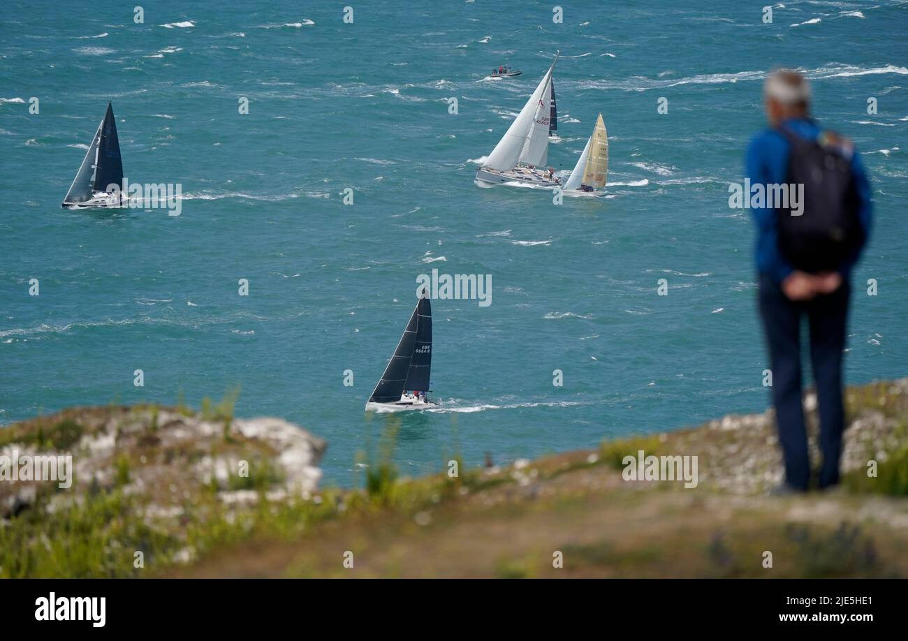 A person looks out to sea as sailing boats pass The Needles, as they take part in the annual Round the Island Race, a one-day, 50 nautical mile yacht race around the Isle of Wight. Starting on the famous Royal Yacht Squadron line in Cowes, the fleet are racing westabout, to The Needles, round St Catherine's Point and Bembridge Ledge buoy, and back into the Solent to the finish line at Cowes. Picture date: Saturday June 25, 2022. Stock Photo