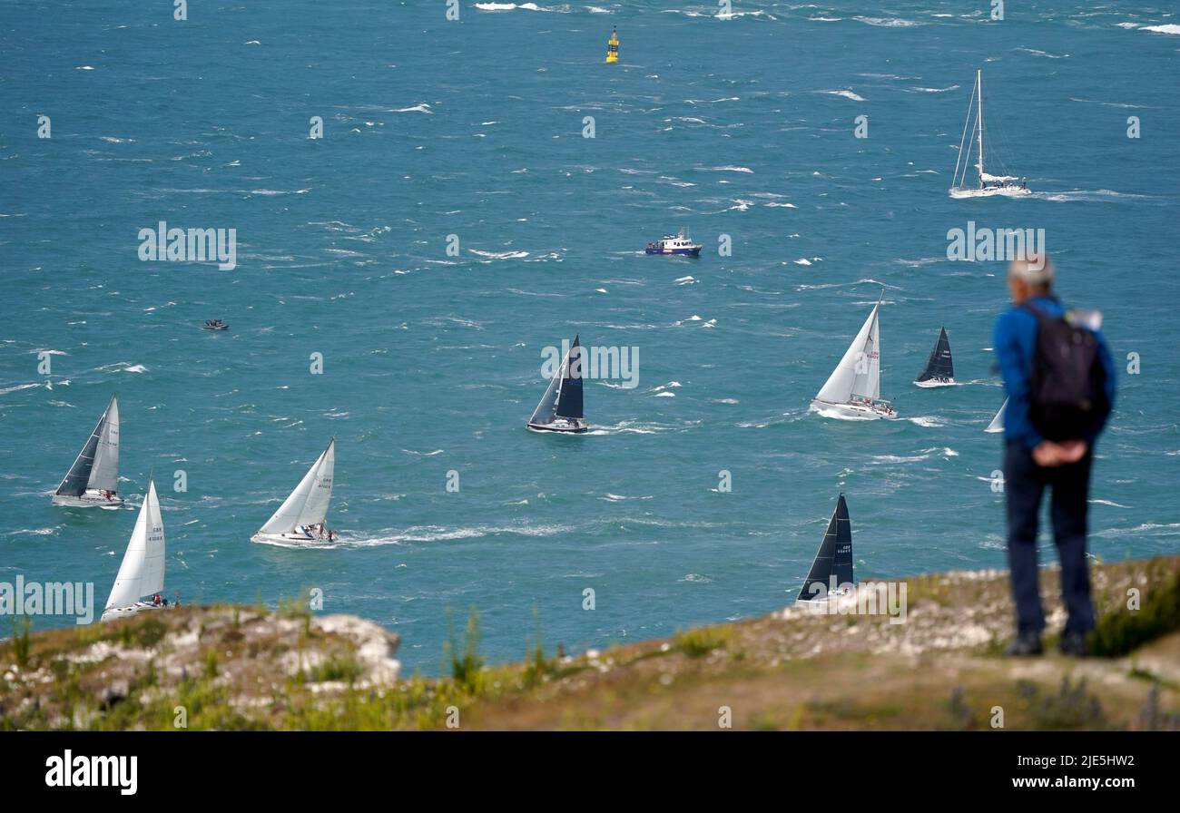 A person looks out to sea as sailing boats pass The Needles, as they take part in the annual Round the Island Race, a one-day, 50 nautical mile yacht race around the Isle of Wight. Starting on the famous Royal Yacht Squadron line in Cowes, the fleet are racing westabout, to The Needles, round St Catherine's Point and Bembridge Ledge buoy, and back into the Solent to the finish line at Cowes. Picture date: Saturday June 25, 2022. Stock Photo