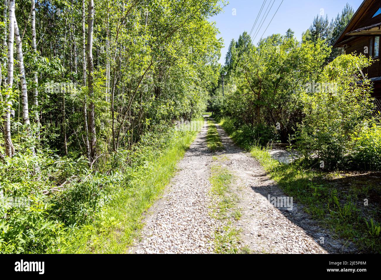 dirt road with ruts covered with gravel in holiday village on sunny summer day Stock Photo