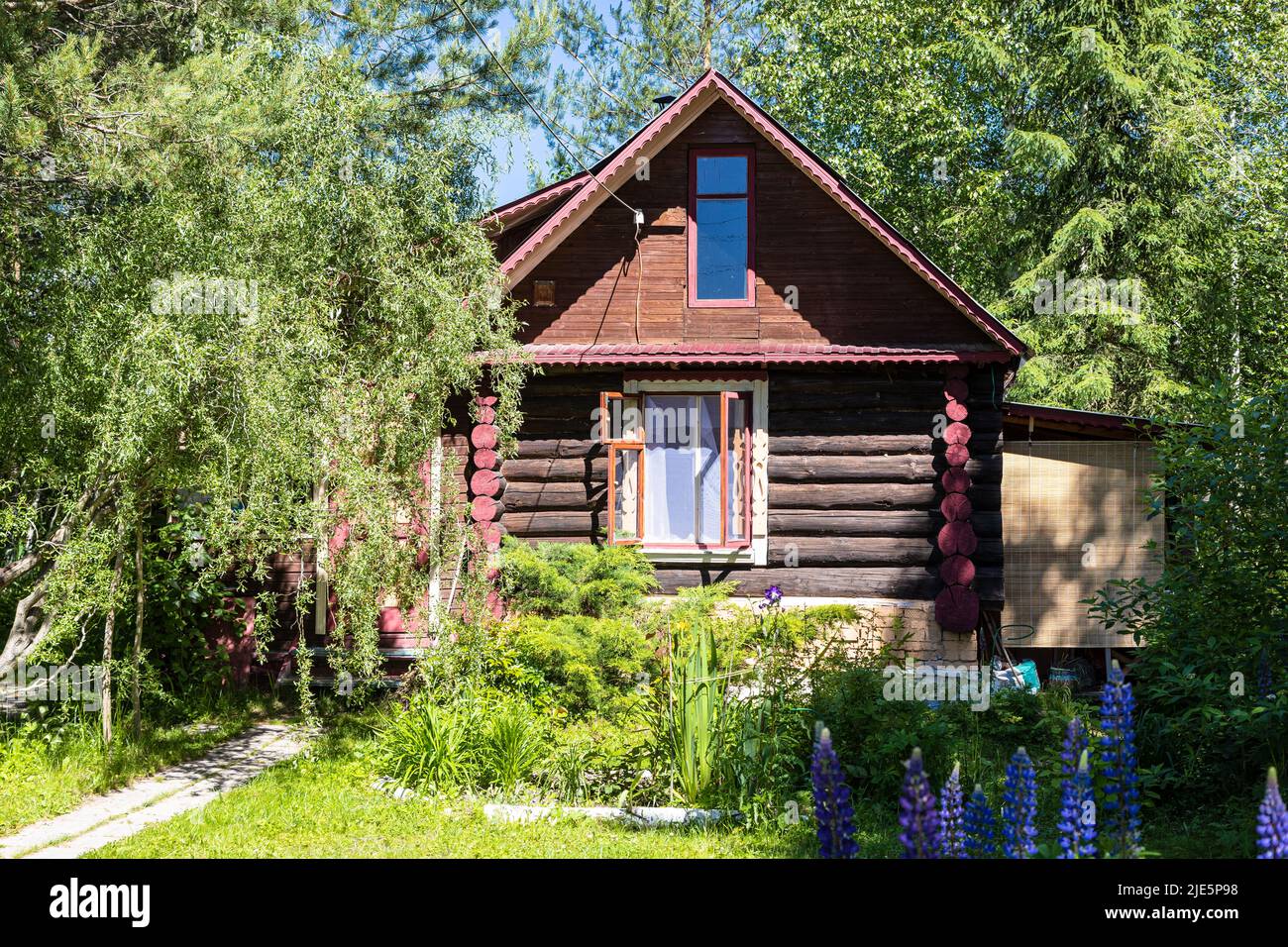 wooden log country house in ornamental garden on sunny summer day Stock Photo