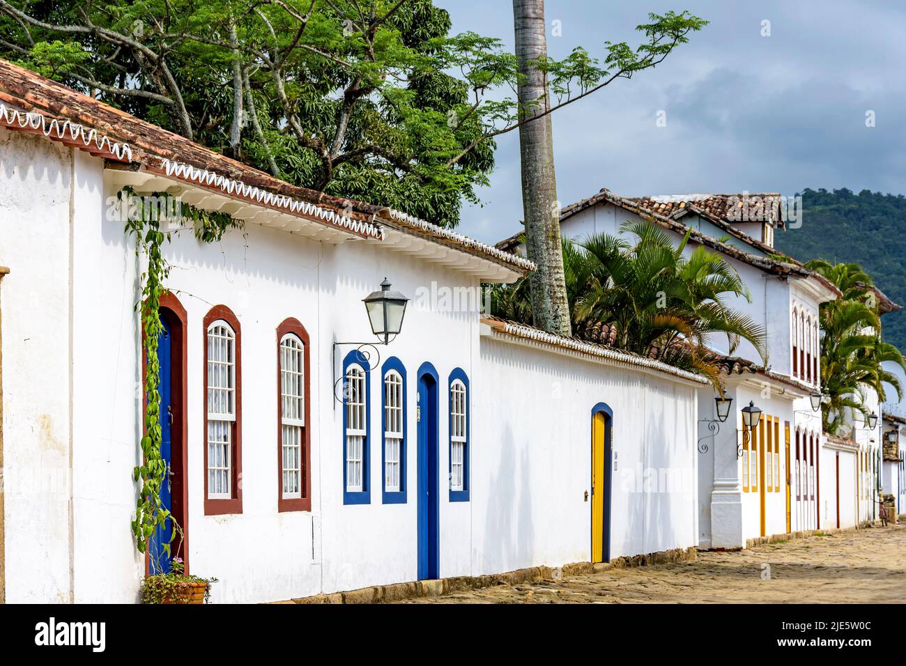 Old colonial style houses on the streets of Paraty city in the state of Rio de Janeiro with forested  hills in backagrond Stock Photo