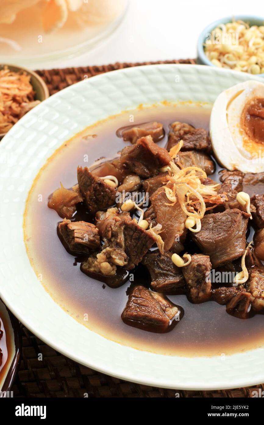 Selected Focus Rawon, Indonesian Traditional Beff Black Soup from East Java. Served on a Bowl wth Shrimp Cracker (kerupuk Udang) and Chilli Paste and Stock Photo