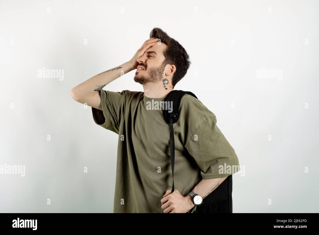 Caucasian young man wearing t-shirt posing isolated over white background suffering headache and holding hands on forehead. Education in university co Stock Photo