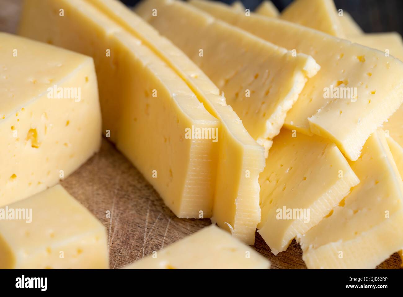 sliced natural cow's milk cheese, fresh yellow milk cheese on a board