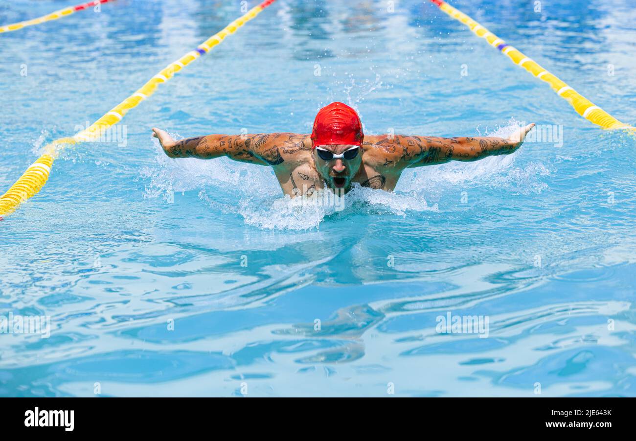 Live portrait of young sportive man, professional swimmer in goggles