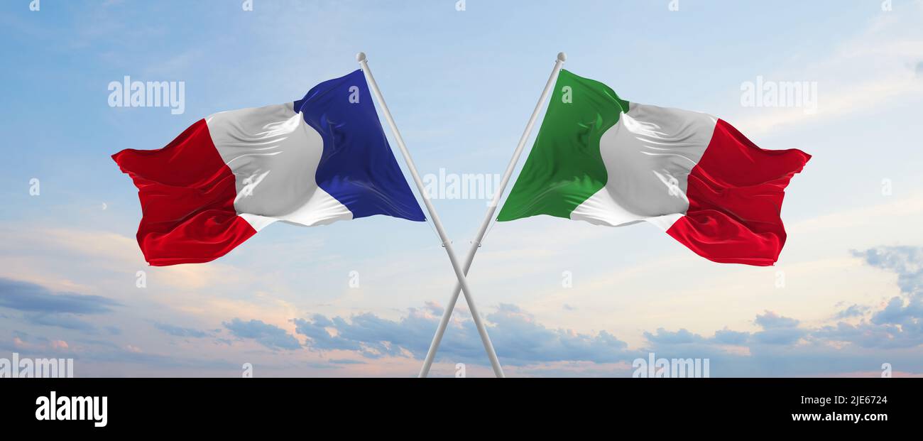 two crossed flags France and Italy waving in wind at cloudy sky ...