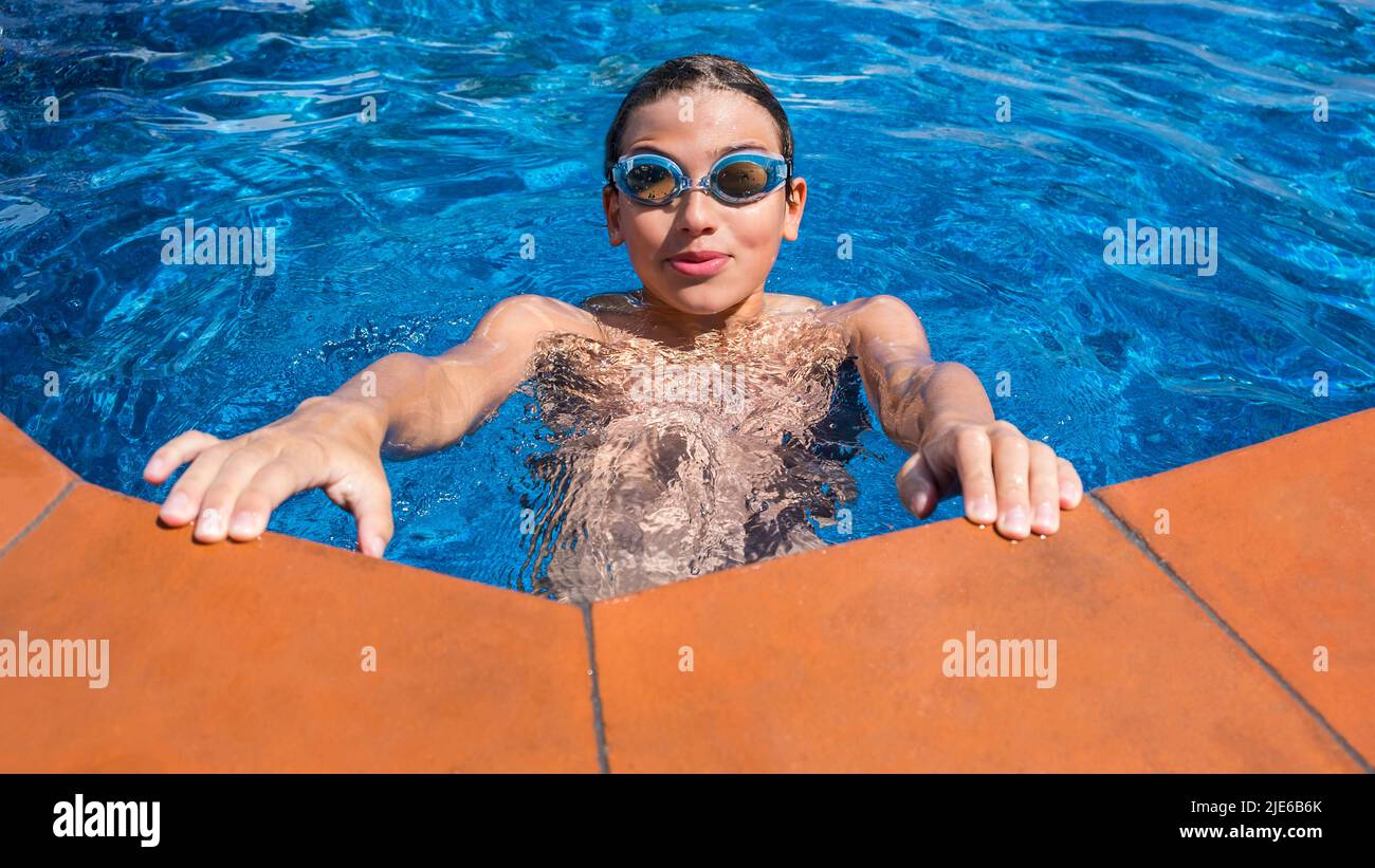 Portrait of a smiling boy in the outdoor pool. Teenager in swimming