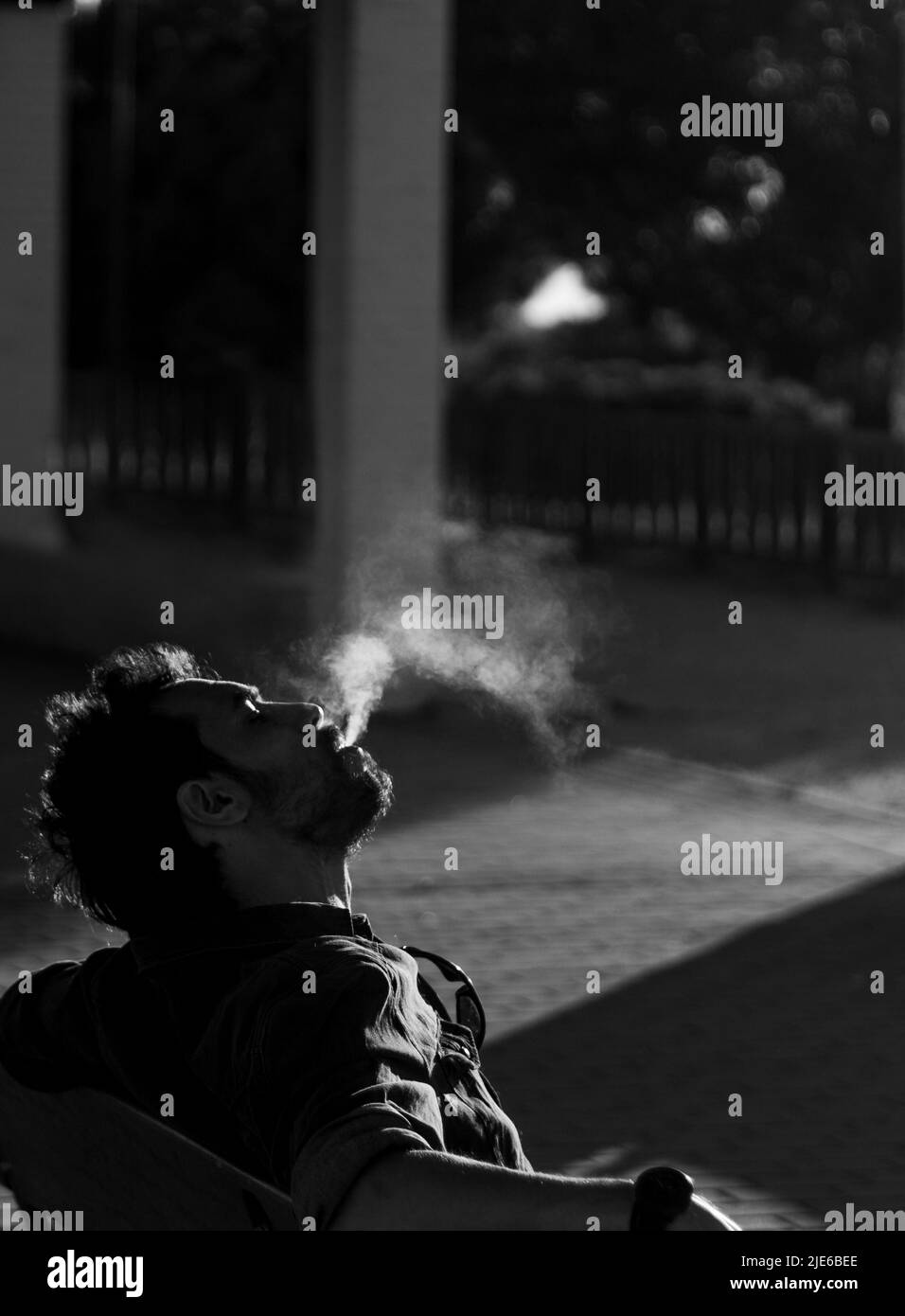 thoughtful man smoking a cigarette alone in black and white selective focus Stock Photo