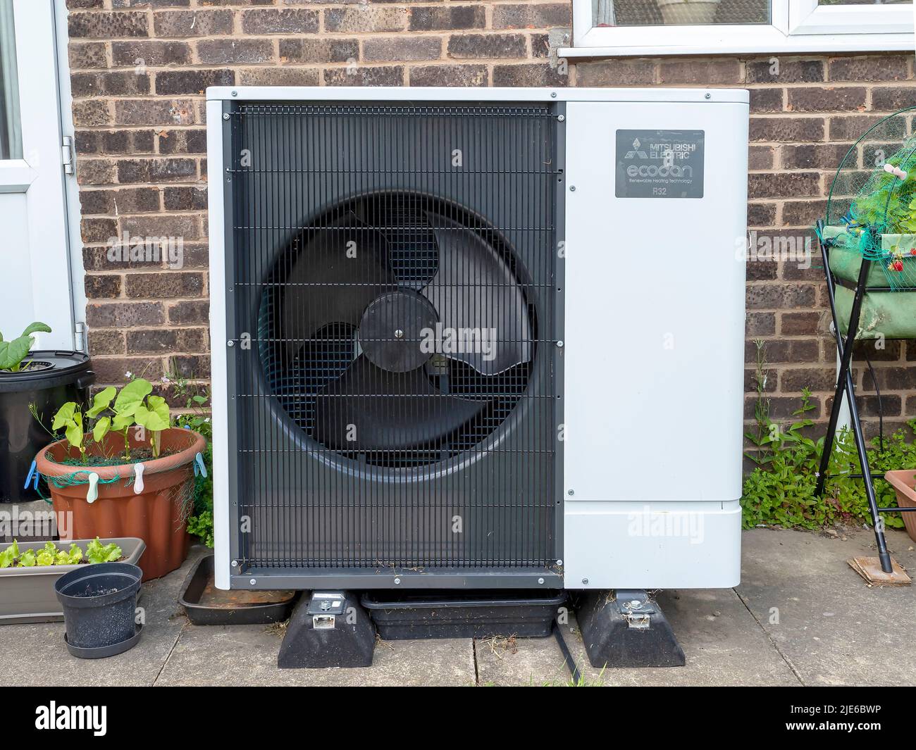 Mitsubishi Ecodan heat pump in a garden in front of a brick house wall Stock Photo